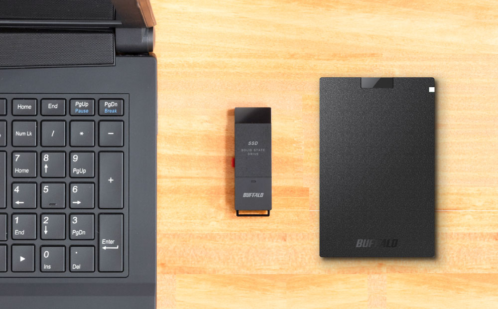 Buffalo SSD solid state drive next to black laptop on wood table